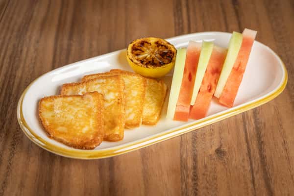 A plate featuring slices of grilled halloumi cheese paired with fresh watermelon sticks.