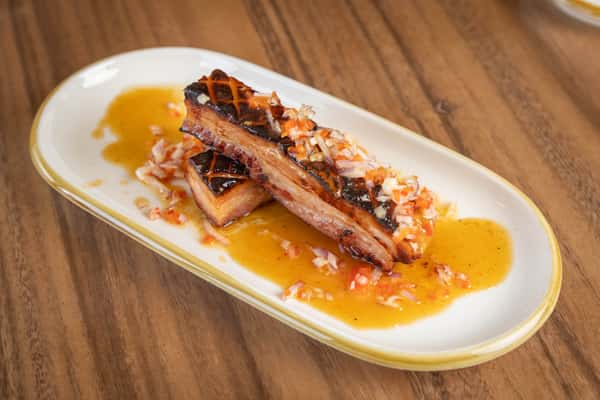 A close-up of grilled octopus tentacles resting on a bed of sauce or puree.