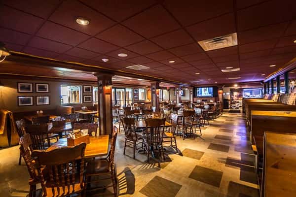 Another angle of the inside of the Brew Pub with wooden tables and chairs with windows in the back
