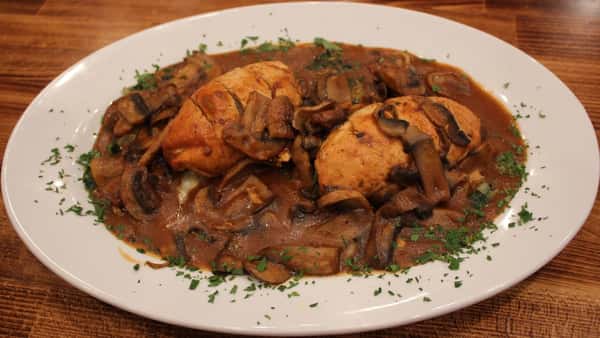 Chicken Marsala with tender chicken breasts in a rich mushroom wine sauce, sprinkled with parsley and served on a white ceramic dish.