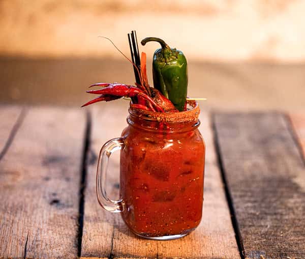 Cocktail with a crawfish and jalapeño garnish