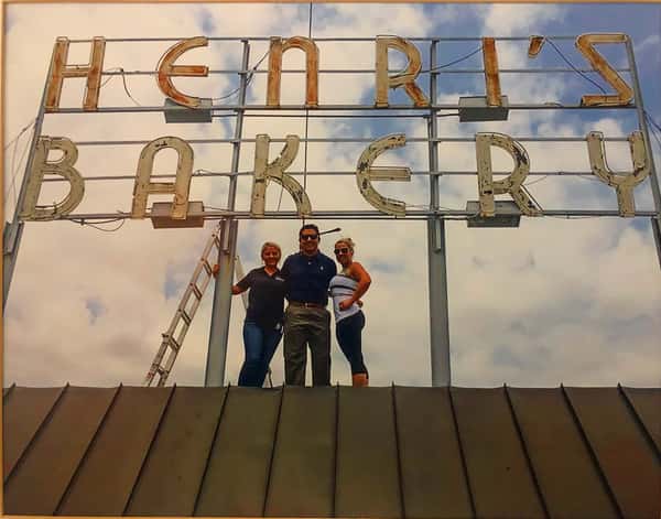 Three of the family members standing in front of the building's Henri's Bakery sign