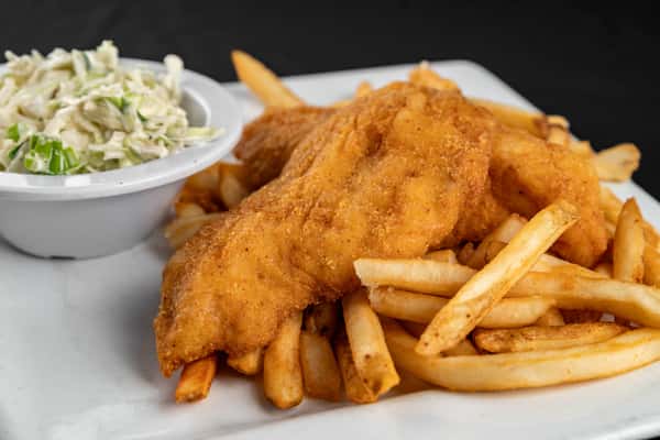 Golden-fried fish fillets served atop seasoned French fries with a side of creamy coleslaw, presented on a square white plate for a classic comfort food dish.