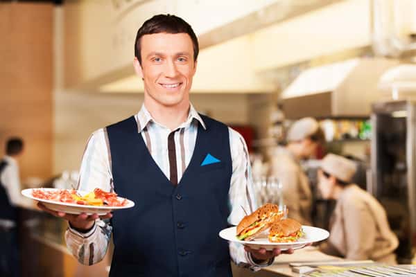 Waiter carrying two plates with sandwich. man looking into camera and holding breakfast
