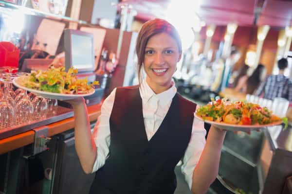 Pretty barmaid holding plates of salads in a bar
