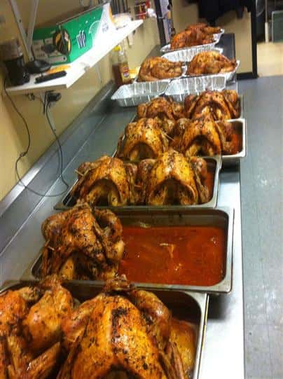 whole rotisserie chickens in aluminum trays and sauce on bottom