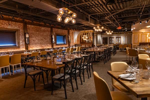 Large restaurant dining area with exposed brick walls, wood accents, and set tables.