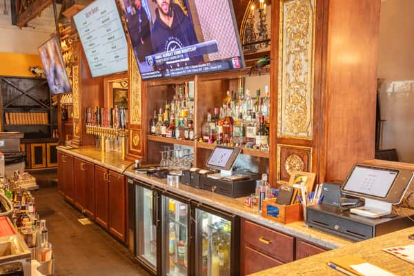 Warm wood bar interior with liquor shelves, beer taps, and TVs creating a lively brewery restaurant atmosphere
