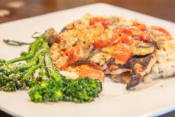 Chicken marsala with mushrooms and creamy sauce served over rice with broccolini at an upscale casual restaurant