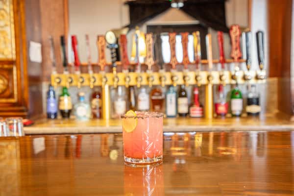 Pink citrus cocktail with rosemary garnish and lemon served in a tall glass at a craft brewery bar