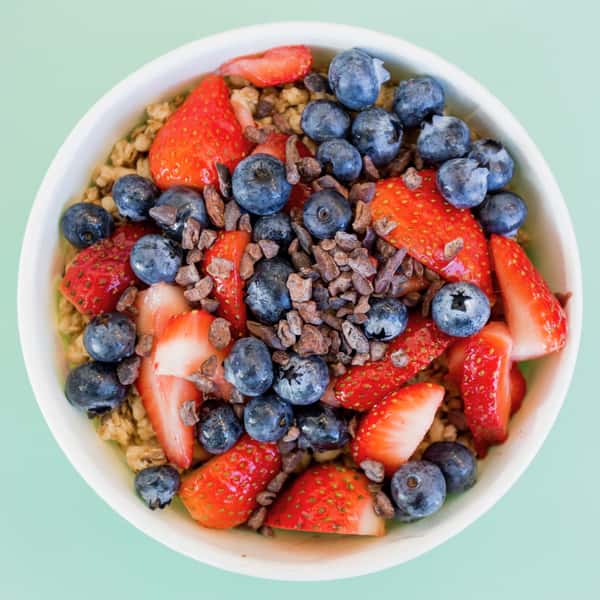 The ABC Bowl from Jan's Health Bar, an açai bowl blended with açai, strawberry, bananas, almond butter, chocolate protein, and almond milk and topped with granola, blueberries, strawberries, cacao nibs, and a drizzle of agave. 