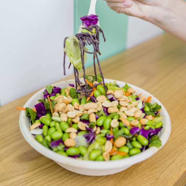 Tsunami Bowl with rice noodles, mixed greens, shredded carrots, green onions, cilantro, mint, edamame, peanuts & cucumbers tossed with a peanut sauce.
