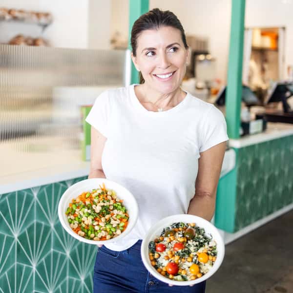 Poppy Holguin holding a Caesar Salad and a Tsunami Bowl.