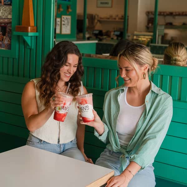 Two friends drinking Strawberry Delight smoothies from Jan's Health Bar.