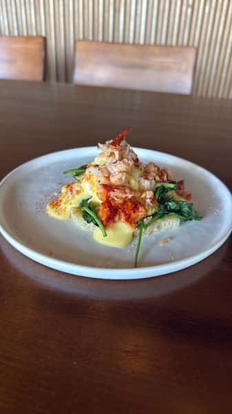 Plated seafood appetizer topped with diced tomatoes and fresh greens over a creamy sauce