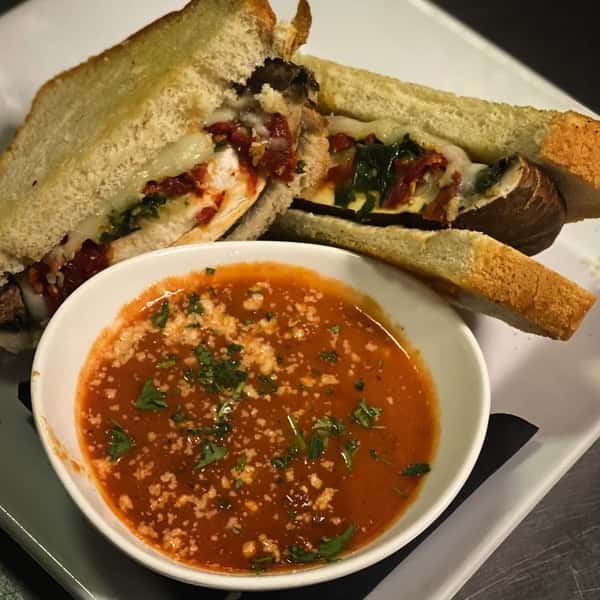 Grilled panini with a cup of hearty vegetable soup on the side