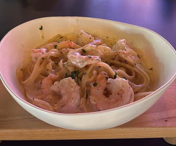 Shrimp fettuccine in a creamy garlic sauce, garnished with herbs, in a white bowl