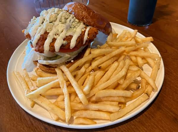 Crispy fried chicken sandwich drizzled with sauce on a toasted bun, served with fries