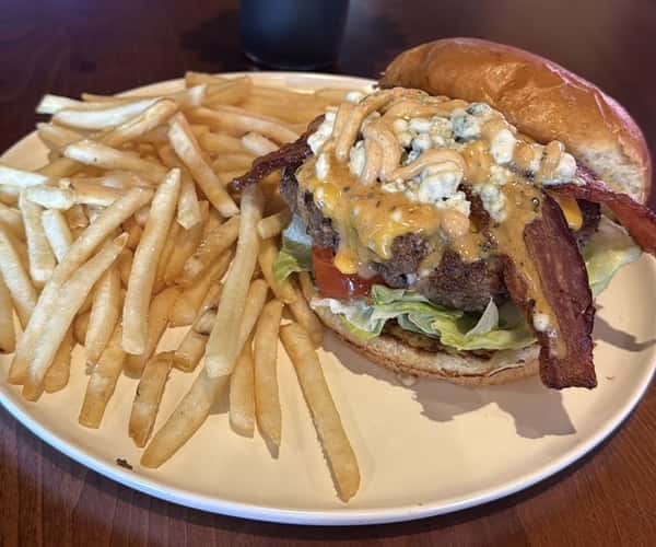 Bacon cheeseburger topped with melted cheese and crispy bacon, served with a side of fries