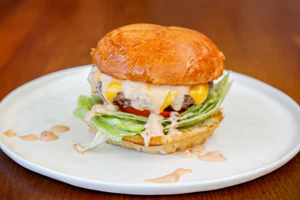 Cook'd OG Burger with fresh lettuce, tomato and toppings on a toasted bun