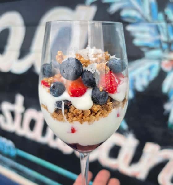 Layered yogurt parfait with granola, fresh blueberries, and strawberries in a wine glass