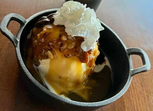 Warm skillet dessert topped with caramel sauce and whipped cream
