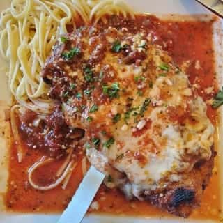 Chicken Parmesan covered in tomato sauce and melted cheese, served with spaghetti.
