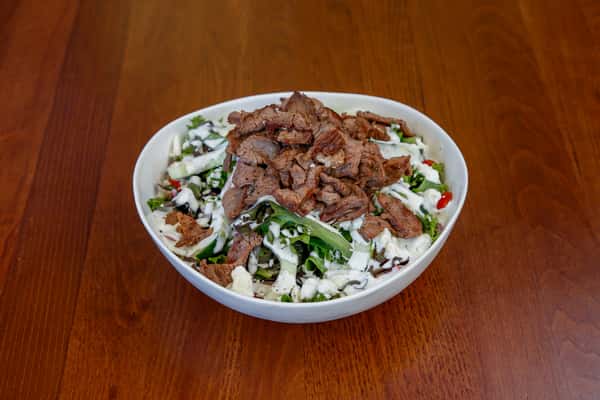 Fresh salad topped with sliced tri-tip steak and vegetables