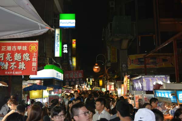 Crowds exploring brightly lit food stalls at the Shilin Night Market in Taipei, Taiwan, the inspiration for Shihlin Taiwan Street Snacks.