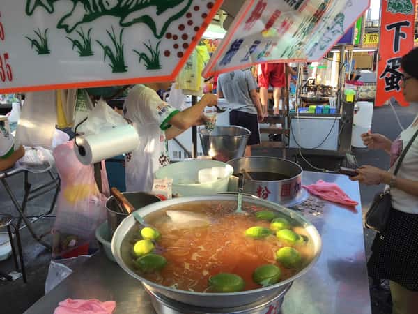 Taiwanese street vendor serving a chilled citrus jelly drink from a large bowl filled with fresh lime