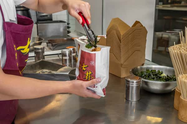 employee serving popcorn chicken into bag