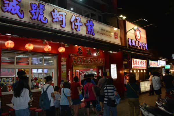 Guests gathered outside a brightly lit Taiwanese street food stall at the Shilin Night Market in Taipei, Taiwan.