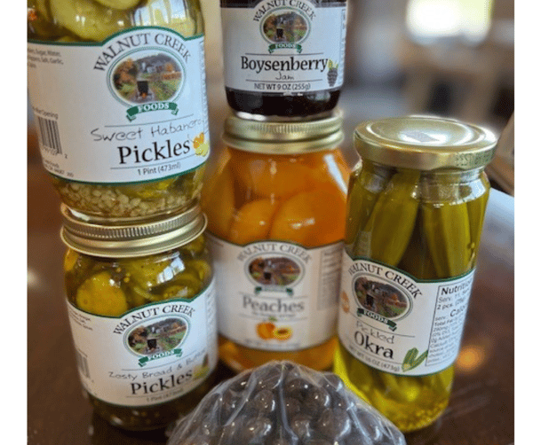 Walnut Creek Foods pickles, peaches, boysenberry jam, and pickled okra jars on table