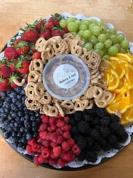 Fruit platter with berries, grapes, orange slices and pretzels around a deli dip.