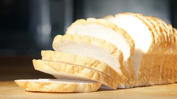 Freshly sliced loaf of white bread on a wooden surface.