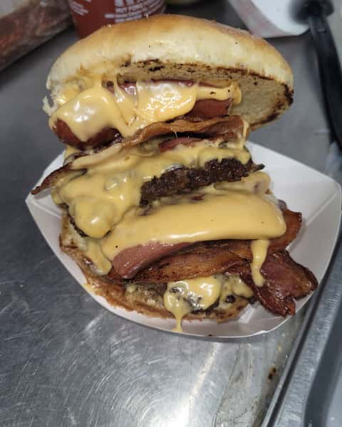 Stacked double bacon cheeseburger with melted cheese, served on a plate
