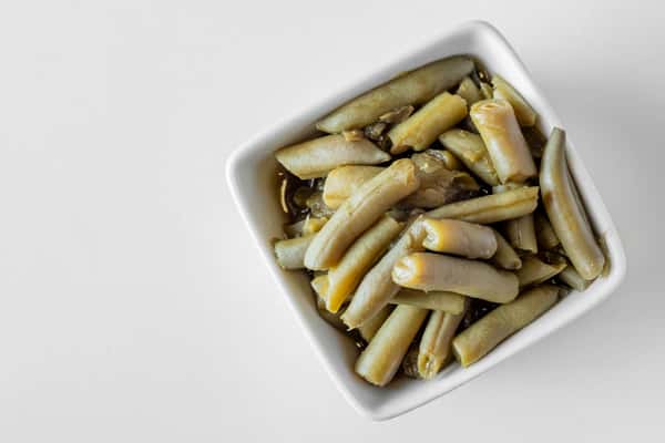 A white bowl filled with seasoned Italian green beans