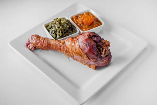 A close-up of a stuffed smoked turkey leg with herb seasoning on a white plate