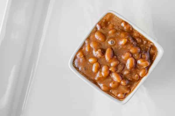 A white dish filled with hearty baked beans