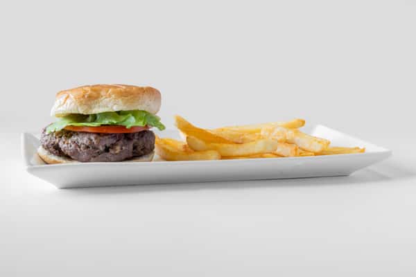 A hamburger with lettuce and toppings served alongside golden french fries on a white plate