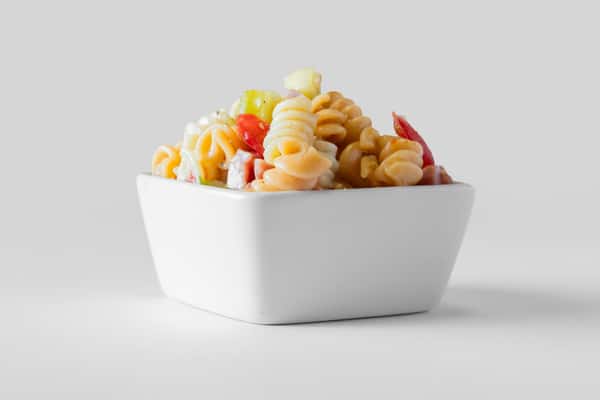 A white bowl filled with a colorful pasta salad with vegetables