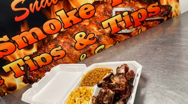 BBQ pork ribs and tips in a to-go container with baked beans and macaroni salad.
