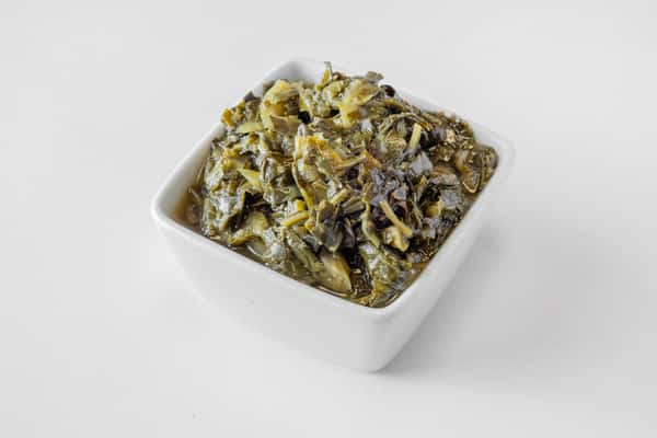 A white bowl filled with seasoned collard greens