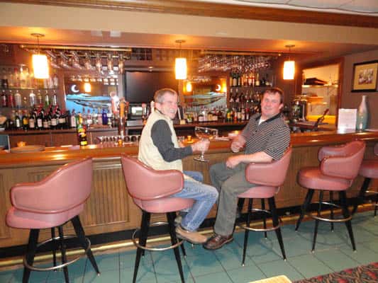 Two men sitting in bar stools at the bar.