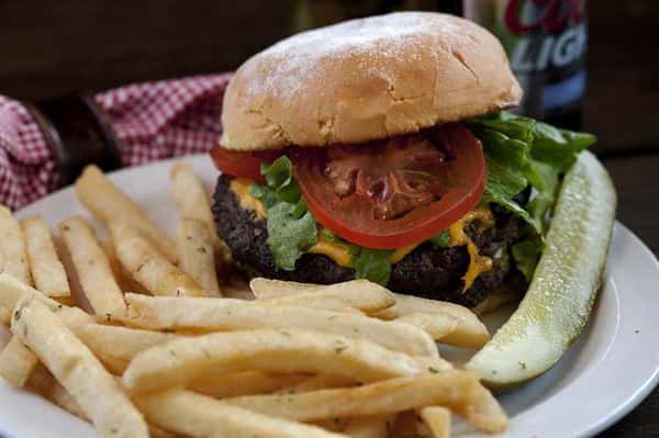 Cheeseburger with lettuce and tomato with a side pickle and french fries,