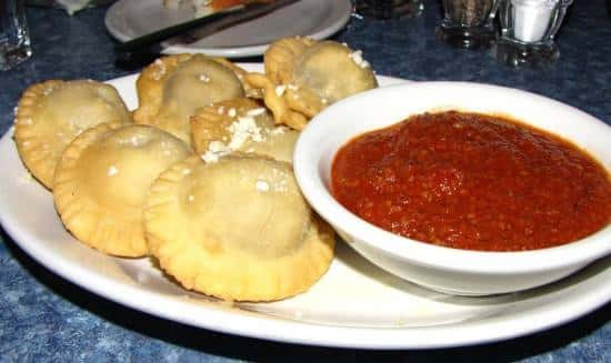 Toasted ravioli with a bowl of bolognese sauce in the center.