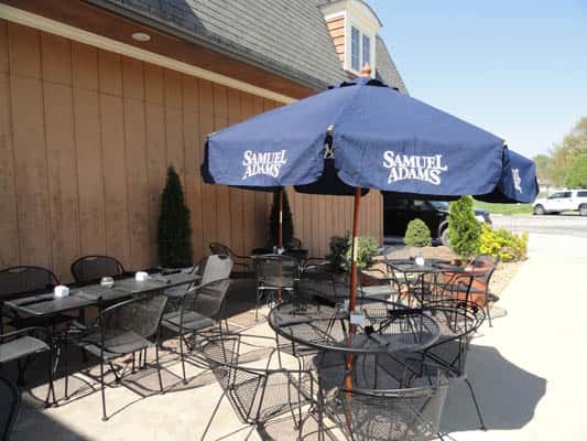 Outside of restaurant, tables setup, one with an umbrella