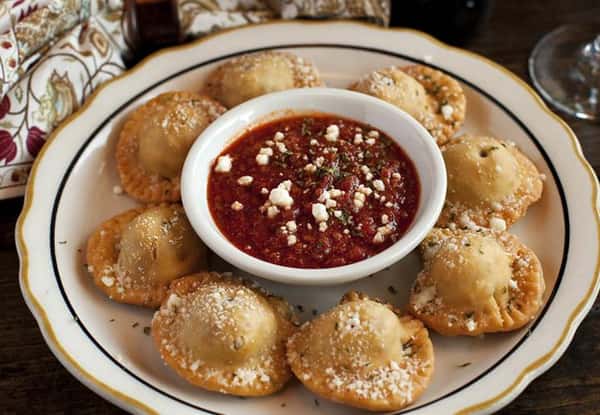 Toasted ravioli with a bowl of bolognese sauce in the center.