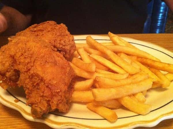 Fried chicken on a plate with a side of french fries.