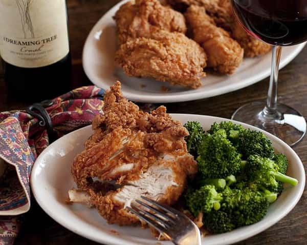 Two plates on a table with fried chicken, one with a side of broccoli.